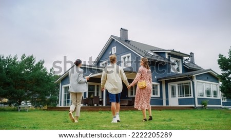 Real Estate Agent Showing a Beautiful Big House to a Young Successful Couple. People Standing Outside on a Warm Day on a Lawn, Talking with Businesswoman, Discussing Buying a New Home.