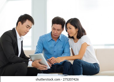 Real Estate Agent Showing Couple A House Plan On The Digital Tablet