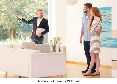 Real Estate Agent Showing Home Interior For Sale To Young Couple