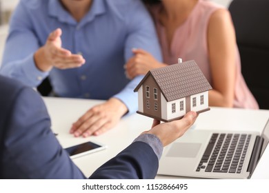 Real Estate Agent Showing House Model To Clients In Office