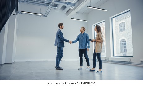 Real Estate Agent Showing a New Empty Office Space to Young Male and Female Hipsters. Entrepreneurs Meet the Broker and They Hand Shake. They Wish to Purchase or Rent.