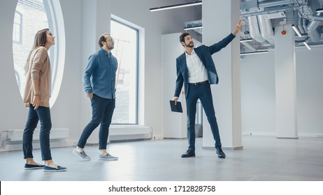 Real Estate Agent Showing A New Empty Office Space To Young Male And Female Hipsters. Entrepreneurs Meet The Broker With A Tablet And Discuss The Facility They Wish To Purchase Or Rent.