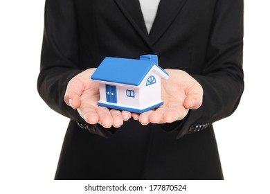 Real estate agent showing new house in mini size. New home owner concept. Realtor showing holding house model. Buying new home conceptual image with business woman in suit isolated on white background - Powered by Shutterstock