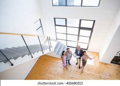 Real estate agent showing new house to couple with digital tablet - Powered by Shutterstock