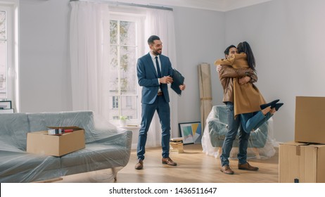Real Estate Agent Shows Bright New Apartment to a Young Couple. Successful Young Couple Becoming Homeowners. Girl Jumps Into His Boyfriend's Arms Hug. Spacious Bright Home with Big Windows. - Shutterstock ID 1436511647