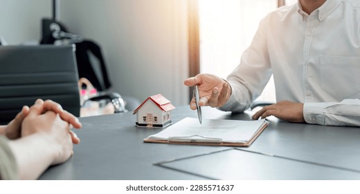 Real estate agent talked about the terms of the home purchase agreement and asked the customer to sign the documents to make the contract legally, Home sales and home insurance concept. - Shutterstock ID 2285571637