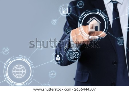 Real estate agent using virtual screen with icons and schemes against grey background, closeup