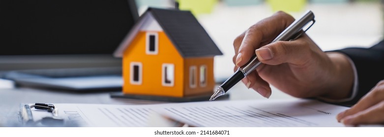 Real Estate Agent Working Sign Agreement Document Contract For Home Loan Insurance Approving Purchases For Client With House Model And Key On Table