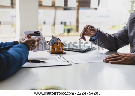 Real estate agents are explaining fees and budgets. Real estate agent discuss home and land purchases with customers after agreeing to a home purchase and loan agreement.