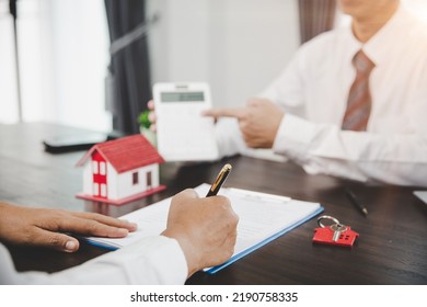 Real Estate Agents Offer Contracts To Purchase Or Rent Residential. Business Person Hands Holding Home Model, Small Building Red House. Mortgage Property Insurance Moving Home And Real Estate Concept