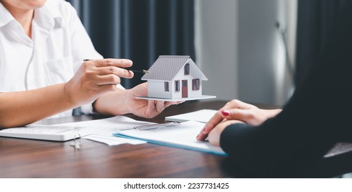 Real estate agents offer contracts to purchase or rent residential. Business person hands holding home model, small building red house. Mortgage property insurance moving home and real estate concept - Shutterstock ID 2237731425
