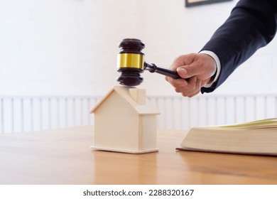 A real estate auctioneer holds a gavel in his hand to knock on a real estate auction when the final price is reached. Real estate auction concept with gavel knocking on mockup house - Powered by Shutterstock