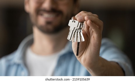 Real Estate. Blurred Closeup Shot Of Young Man Landlord Investor Buyer Seller Renter Tenant Of House Flat Apartment Commercial Realty Holding Key. Focus On Male Hand Giving Or Getting Bunch Of Keys