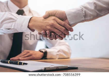 Real estate broker agent and customer shaking hands after signing contract documents for realty purchase, Bank employees congratulate, Concept mortgage loan approval.