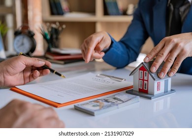 Real estate broker agent presenting and consult to customer to decision making sign insurance form agreement, home model, concerning mortgage loan offer for and house insurance. - Shutterstock ID 2131907029