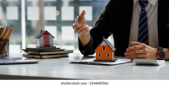 Real estate broker agent presenting and consult to customer to decision making sign insurance form agreement, buy and sell home model, concerning mortgage loan offer for and house insurance - Shutterstock ID 2144683563