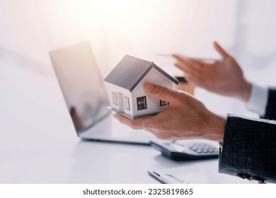 Real estate broker agent presenting and consult to customer to decision making sign insurance form agreement, buy and sell home model, concerning mortgage loan offer for and house insurance - Shutterstock ID 2325819865