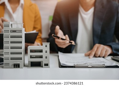 Real estate broker agent presenting and consult to customer to decision making sign insurance form agreement, home model, concerning mortgage loan offer in office