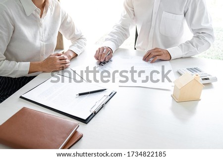 Real estate broker agent presenting and consult to customer to decision making sign insurance form agreement, home model, concerning mortgage loan offer for and house insurance.