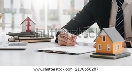 Real estate broker agent presenting and consult to customer to decision making sign insurance form agreement, buy and sell home model, concerning mortgage loan offer for and house insurance
