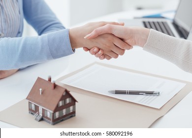 Real estate broker and customer shaking hands after signing a contract: real estate, home loan and insurance concept - Shutterstock ID 580092196