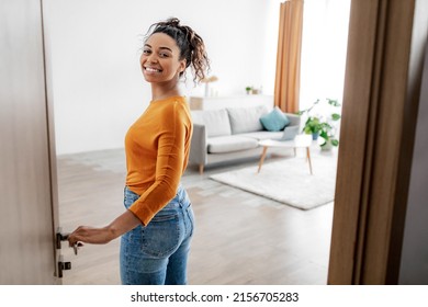 Real Estate. Cheerful African American Female Opening Door Welcoming You To Her New Apartment Entering Living Room And Smiling To Camera Posing At Home. Welcome To My House