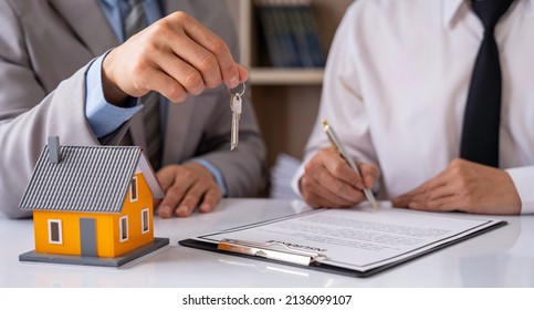 Real estate company to buy houses and land are delivering keys and houses to customers after agreeing to make a home purchase agreement and make a loan agreement. Discussion with a real estate agent - Shutterstock ID 2136099107