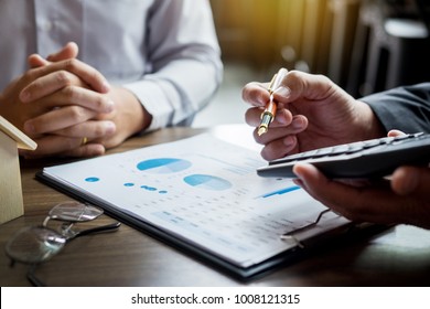 Real Estate concept, Agent holds calculator for present price for loan investment chart graph documents and calculating table payment to customer