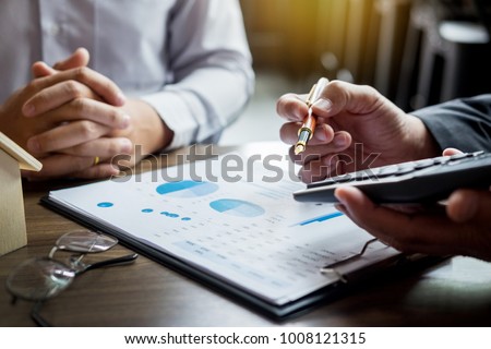 Real Estate concept, Agent holds calculator for present price for loan investment chart graph documents and calculating table payment to customer