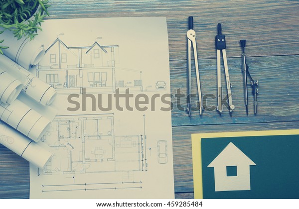 Real Estate concept. Architectural project,
blueprints, blueprint rolls and  divider compass on vintage wooden
table. Top view. Construction background. Engineering tools.
Architect workplace.