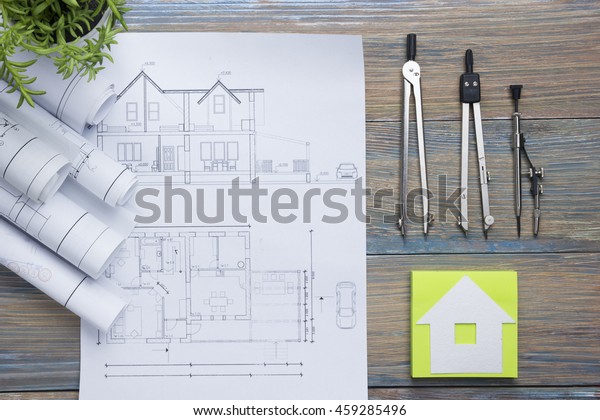 Real Estate concept. Architectural project,\
blueprints, blueprint rolls and  divider compass on vintage wooden\
table. Top view. Construction background. Engineering tools.\
Architect workplace.