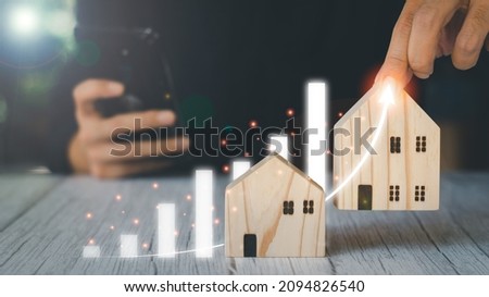 Real estate investment concept. Businessman holding wooden model houses and virtual graph, real estate growth in the future, finance, banking, lending, and trading.
