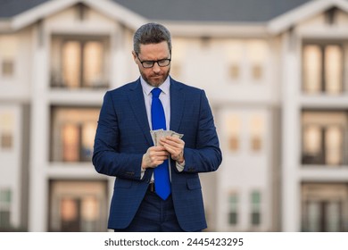Real estate investment. Good payment. Handsome man holding money outdoor. Money in dollar banknotes. Pile of cash, finance, investment and money saving. Broker or real estate agent.