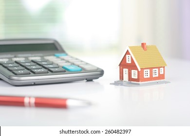 Real estate investment. House and calculator on table.