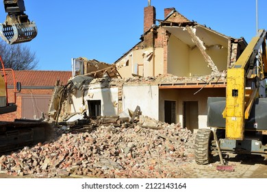 Real estate Investment: old house to be replaced by flats. House dismantled by a bulldozer. Brick Rubble pulled down by a bulldozer on a sunny winter day. Grab crane in action