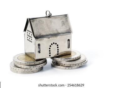  real estate investment on reliable foundation, small silver model house stands on two strong stacks of coins, concept image, isolated on white background with copy space