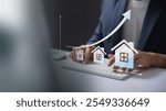 Real Estate Market Growth Concept. Businessman typing on keyboard with rising house icons and graph, symbolizing real estate market growth and investment trends.