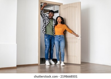 Real Estate Offer. Shocked African American Couple Standing In Opened Doors Hugging Looking At Their New House. Property Ownership Concept. Full Length Shot