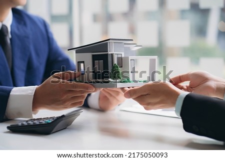 Real estate professionals and clients discussing home purchases, insurance or real estate loans. Home sales agents sit at the office with new homebuyers in the office