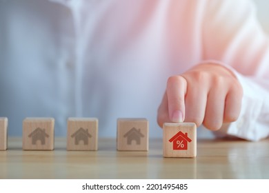 Real estate, Property investment and asset management concept. Interest rates, loan mortgage, house tax, discount and sale price. Hand choosing house with percentage icon on wood cube from may houses. - Shutterstock ID 2201495485