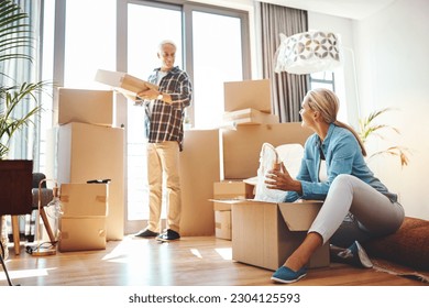 Real estate, property and a senior couple moving house while packing boxes together in their home. Box, investment and retirement with old people unpacking in the living room of their new apartment - Powered by Shutterstock