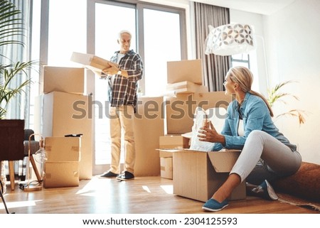 Real estate, property and a senior couple moving house while packing boxes together in their home. Box, investment and retirement with old people unpacking in the living room of their new apartment