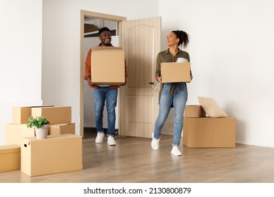 Real Estate Purchase. Happy Black Couple Entering New Home Carrying Cardboard Moving Boxes Indoors. Housing For Family, Property Rent And Ownership Concept. Full Length Shot