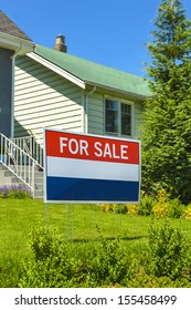 Real Estate Sign "For Sale" on front yard of a house.