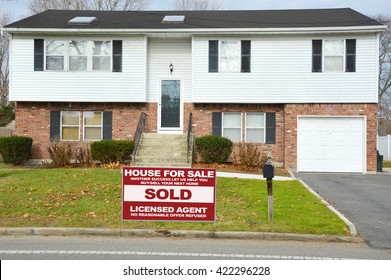 Real estate sold (another success let us help you buy sell your next home) sign Beautiful Suburban Brick Siding High Ranch Home Residential Neighborhood Autumn Day USA