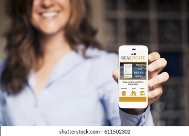 Real Estate Website In A Mobile Phone Screen. Smiling Woman Holding Phone In The Hand. Website Template Design  Specifically Designed And Released.