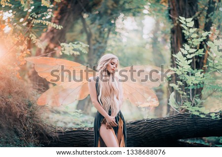 real fairy from magical stories, goddess of nature with transparent wings alone in dense forest, beauty closes her eyes, listens to birds singing, charming lady in the sunlight and with bare legs.