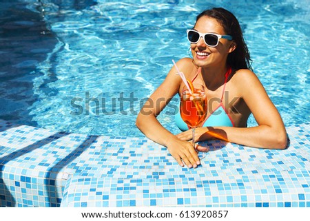 Real female beauty enjoying her summer vacation at swimming pool with alcohol cocktail
