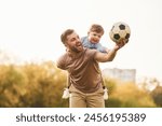 Real football, soccer ball. Happy father with son are having fun on the field at summertime.