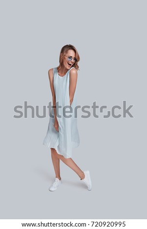 Real fun. Full length of attractive young woman keeping mouth open and smiling while posing against grey background